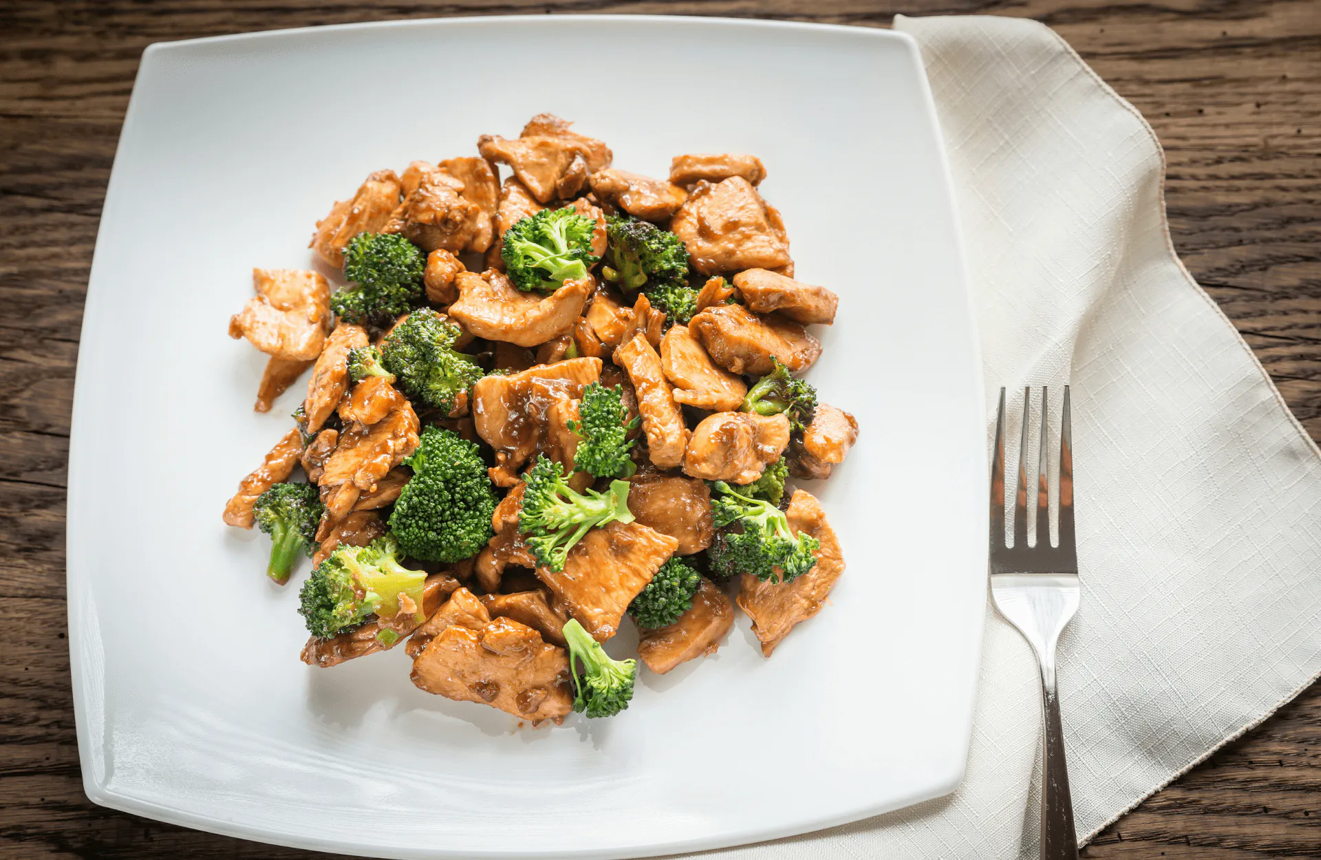 Sautéed chicken and broccoli coated in brown sauce served on a white square plate at Kim's Chinese Food, a Chinese Restaurant in Hampton Sautéed chicken and broccoli coated in brown sauce served on a white square plate at Kim's Chinese Food, a Chinese Restaurant in Hampton